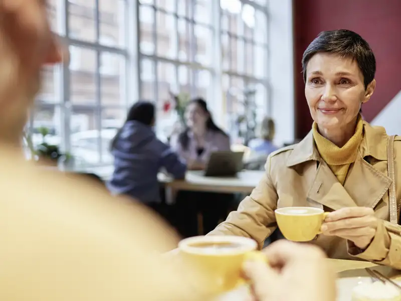 Eine Teilnehmerin einer Studienreise genießt eine Kaffeepause und unterhält sich in einem Jugendstil-Kaffeehaus in Budapest.