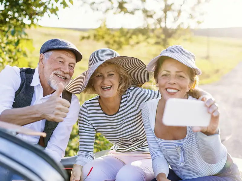 Drei gut gelaunte Teilnehmer einer Studienreise machen bei einem Landausflug in Italien ein gemeinsames Selfie.