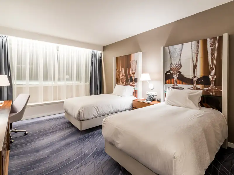 Helles, modernes Zweibettzimmer im Hotel Double Tree by Hilton in Breslau mit Schreibtisch und Fensterfront.