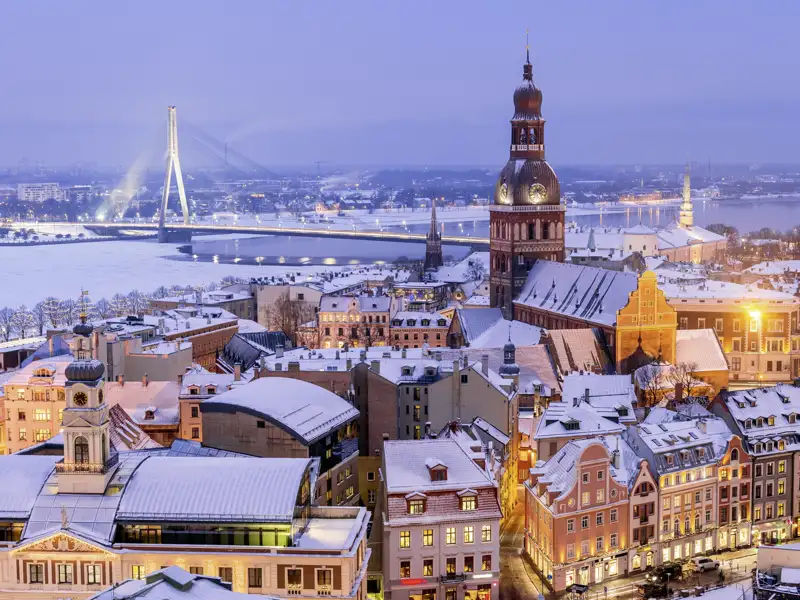 Winterliches Panorama der Altstadt von Riga bei Dämmerung mit dem Dom und der beleuchteten Vanšu Brücke im Hintergrund, wunderschön auch für unsere Studiosus Gruppe zum Bestaunen.