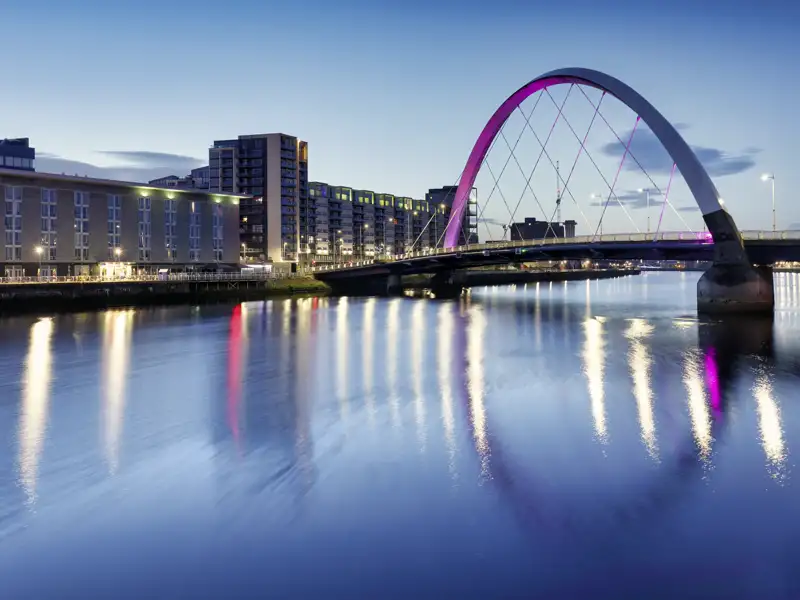 Stimmungsvolle Abendaufnahme der violett beleuchteten Clyde Arc Brücke über den River Clyde in der schottischen Stadt Glasgow. Ein Highlight ihrer Studiosus Eventreise.
