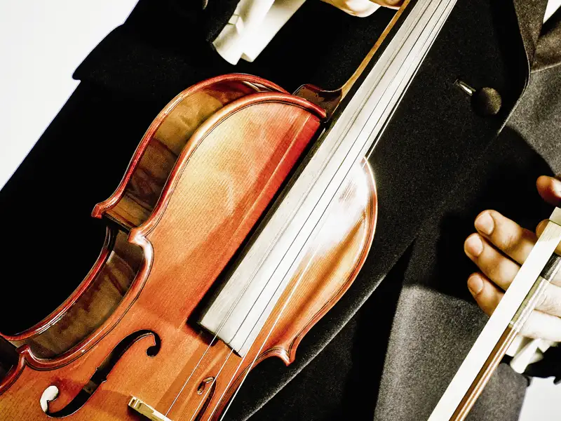 Ein Musiker im Frack hält seine Violine, bereit für das Neujahrskonzert bei einer Eventreise in der Staatsoper Berlin.