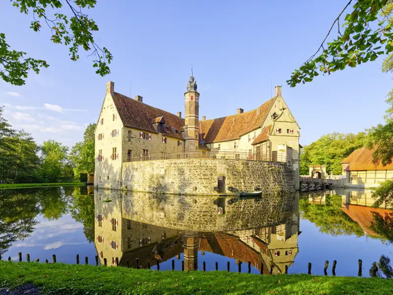 Die wehrhafte Burg Vischering im Münsterland spiegelt sich an einem sonnigen Tag im ruhigen Wasser des Burggrabens, auch sie auf ihrer Studiosus Studienreise werden diese wunderschön gelegene Burg auf ihrer Reise besichtigen dürfen.