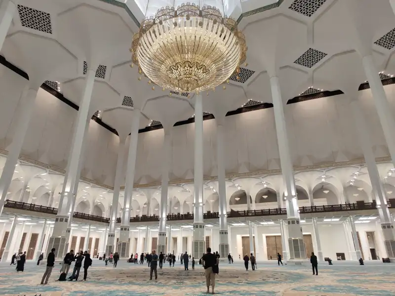 Weitläufige, helle Gebetshalle der modernen Djamaa El Djazair Moschee in Algier mit hohen weißen Säulen und einem Kristalllüster.