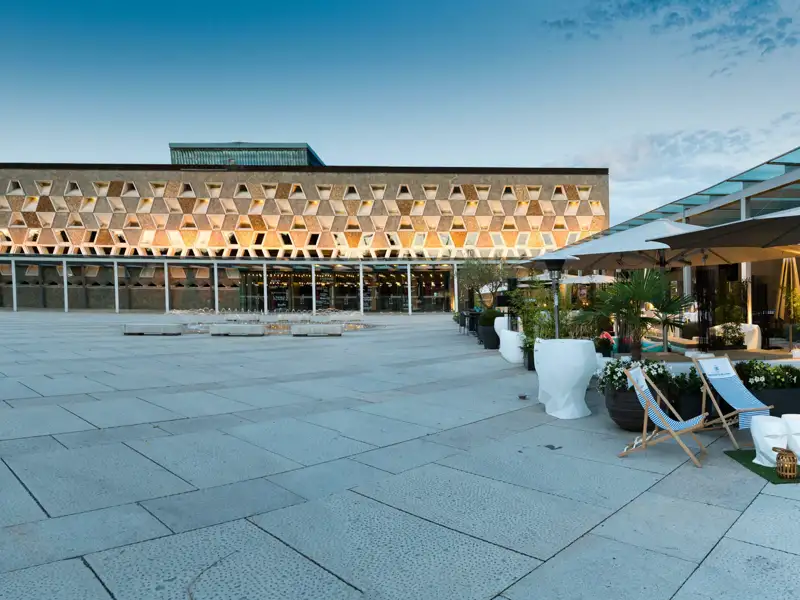 Moderne Architektur des Grand Théatre in Luxemburg bei Dämmerung mit beleuchteter Wabenfassade und Vorplatz mit Terrasse, ein Highlight jeder Studiosus Eventreise