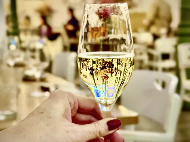 Nahaufnahme eines Sektglases, gehalten von einer Frau beim musikalischen Silvester-Dinner einer Eventreise in Madrid.