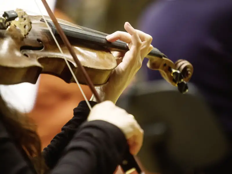 Nahaufnahme der Hände einer Musikerin, die während des musikalischen Dinners einer Studiosus Eventreise Violine spielt.