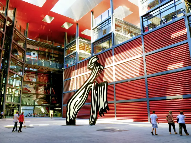Studienreise in Madrid: Besucher im Innenhof des Reina Sofía Museums mit Roy Lichtensteins Skulptur und roter Fassade.