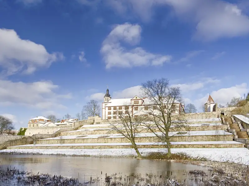Winterliche Ansicht von Schloss Wilhelmsburg in Schmalkalden mit schneebedeckten Terrassen und einem zugefrorenen Teich. Ein schönes Fotomotiv während Ihrer Eventreise.