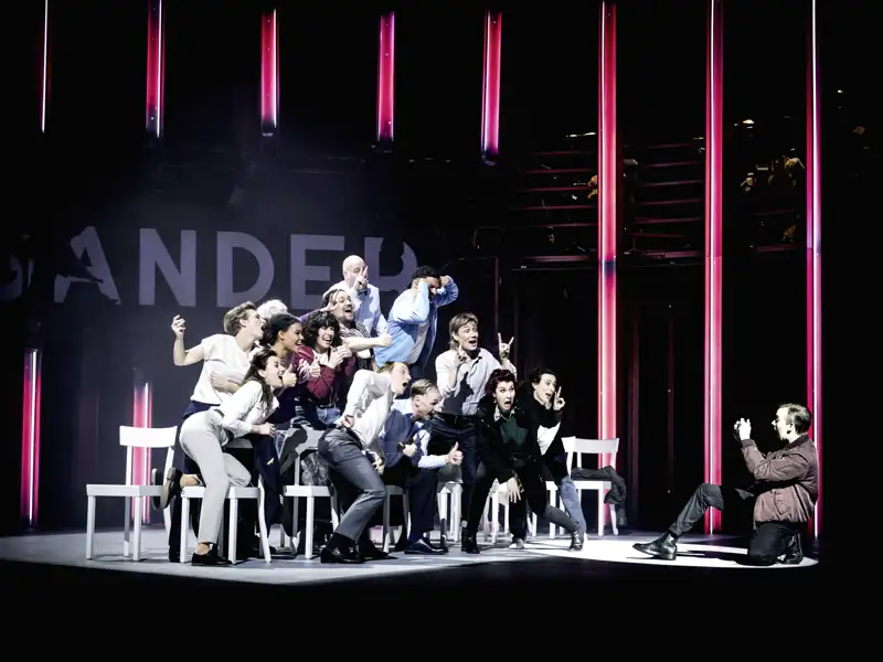 Lebhafte Szene aus dem Musical 'Come From Away': Das Ensemble posiert auf der Theaterbühne in Regensburg für ein Foto.