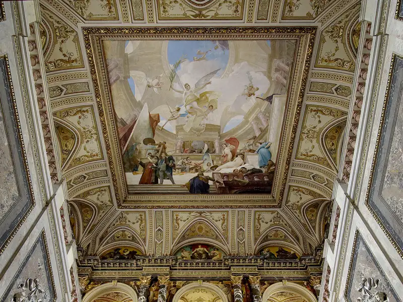 Blick nach oben zum prunkvollen Deckenfresko und den Goldverzierungen in der Großen Galerie von Schloss Schönbrunn in Wien. Sie besuchen das Schloss im Rahmen einer Gruppenreise.