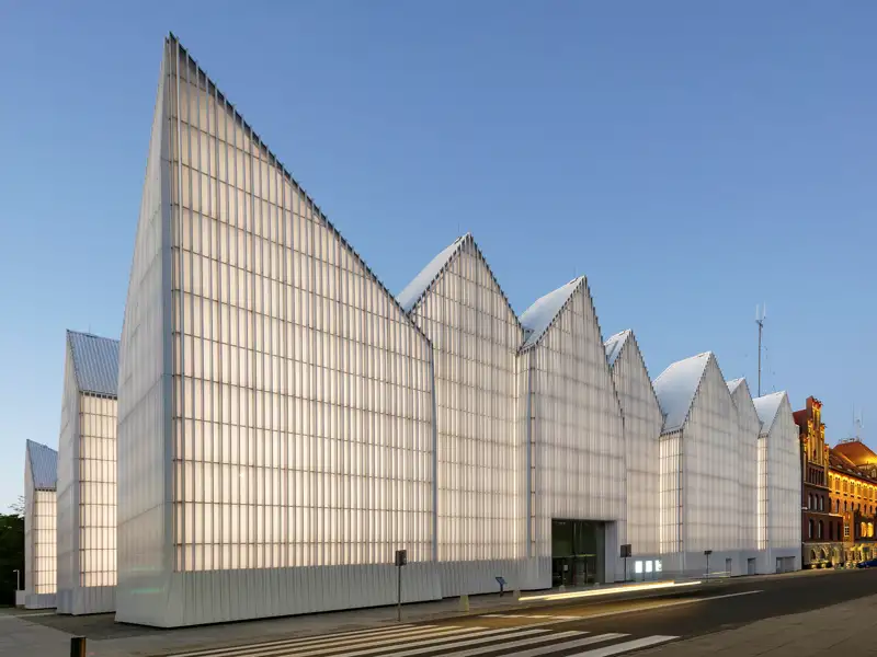 Die moderne Fassade der Stettiner Philharmonie leuchtet bei Dämmerung, ein architektonisches Highlight der Studienreise mit Studiosus nach Polen.