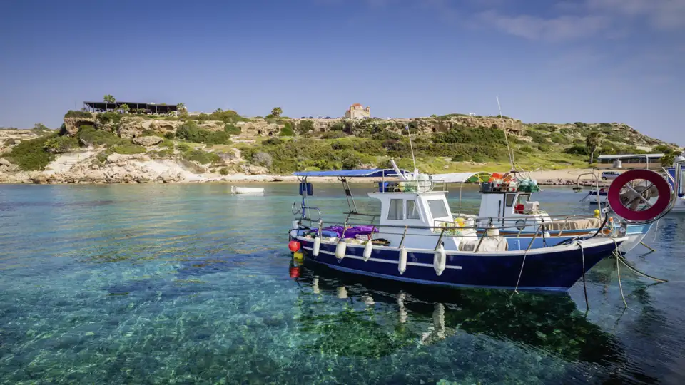 Unsere Reise führt uns auch in den Küstenort Paphos, wo die Cafés am Hafen zu einer Pause einladen und wir Fischerboote, die im glasklaren Wasser ankern, beobachten können.