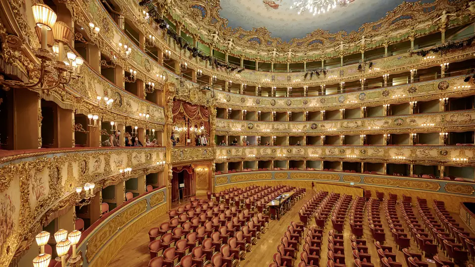 Auf unserer Gruppenreise mit Studiosus erleben wir den opulenten Innenraum des Teatro La Fenice in Venedig. Ein Highlight der Eventreise sind die goldverzierten Logenränge und die roten Sitze des Opernhauses.