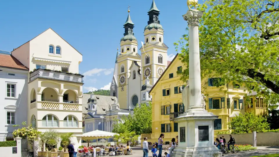 Der barocke Brixner Dom an einem sonnigen Tag, gesehen vom belebten Domplatz mit seinen Cafés und historischen Gebäuden, ein toller Ausblick auf unserer Studiosus Gruppenreise.