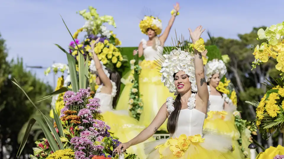 Auf unserer Gruppenreise mit Studiosus bewundern wir Tänzerinnen in aufwendigen gelben Blumenkostümen winken von einem prächtigen Festwagen beim Blumenfest in Funchal.