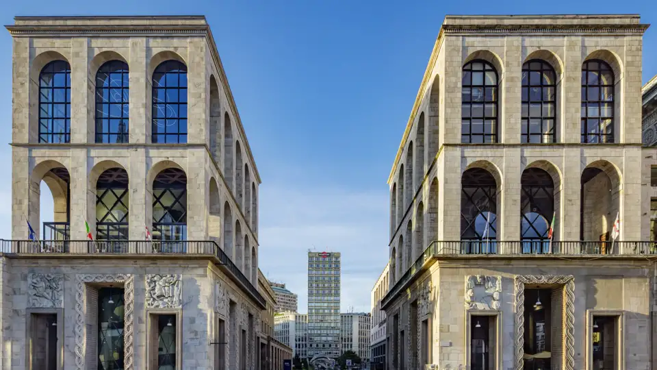 Auf unserer Eventreise mit Studiosus nach Italien bewundern wir symmetrische Fassaden des Palazzo dell’Arengario in Mailand mit großen Rundbogenfenstern und Blick auf die Torre Velasca.