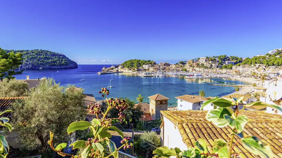 Auf Ihrer Gruppenreise habe Sie einen malerischen Blick über mediterrane Ziegeldächer, auf die sonnige Bucht und den Hafen von Port de Sóller auf Mallorca.