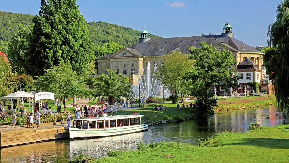 Reisende bei einer Bootsfahrt auf der Fränkischen Saale in Bad Kissingen mit Blick auf den prachtvollen Regentenbau im Kurpark, ein Highlight auf unserer Rundreise mit Studiosus.
