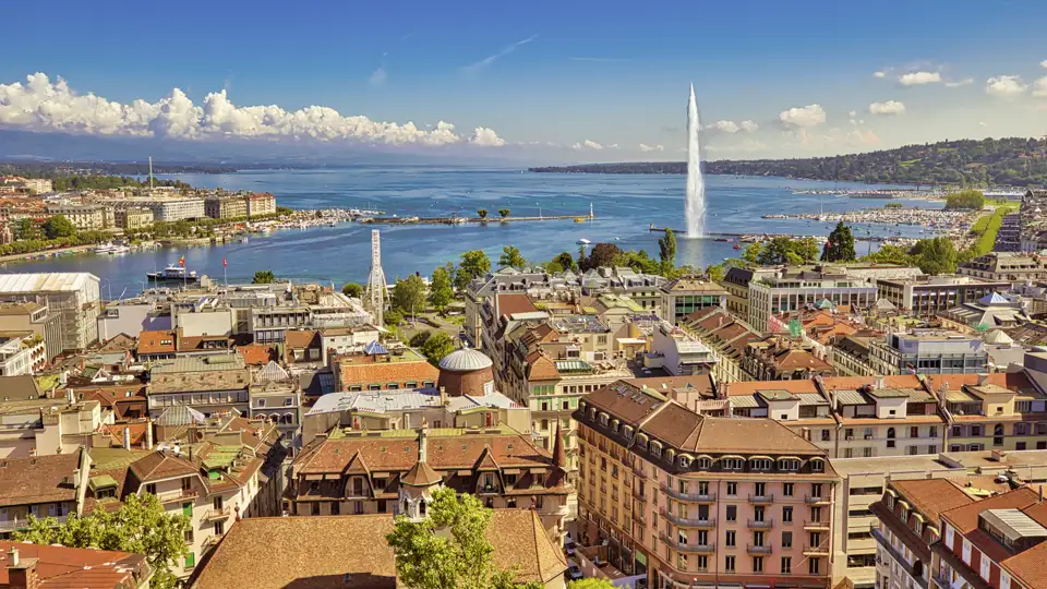 Panoramablick über die Dächer der Genfer Altstadt auf den Genfer See mit der berühmten Wasserfontäne, dem Jet d'Eau. Wunderschöner Ausblick für unsere Studiosus Reisenden auf ihrer Eventreise.
