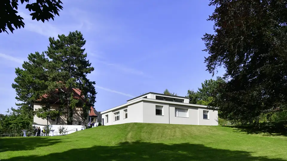 Auf unserer Studienreise besichtigen wir das modernistische Haus am Horn in Weimar, ein Meilenstein der Bauhaus-Architektur auf einem Rasenhügel.