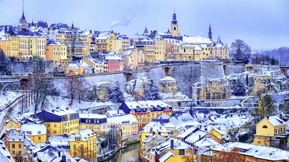 Winterlicher Blick auf die verschneite Altstadt von Luxemburg mit bunten Häusern und dem Fluss Alzette im Stadtteil Grund.