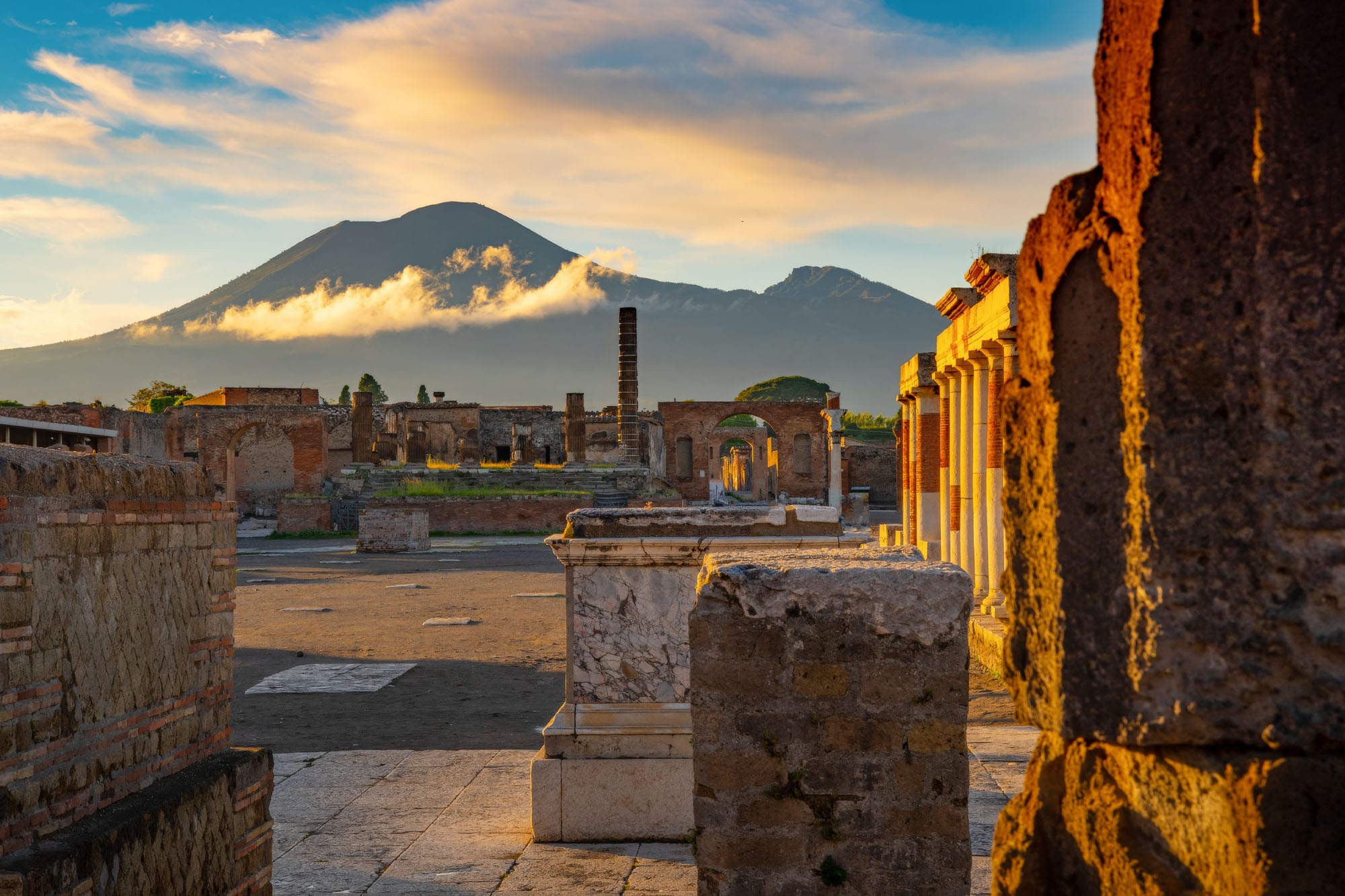 Pompeji ist einer der meistbesuchten Orte Italiens. Ausgrabungen im Vordergrund, Berge im Hintergrund.