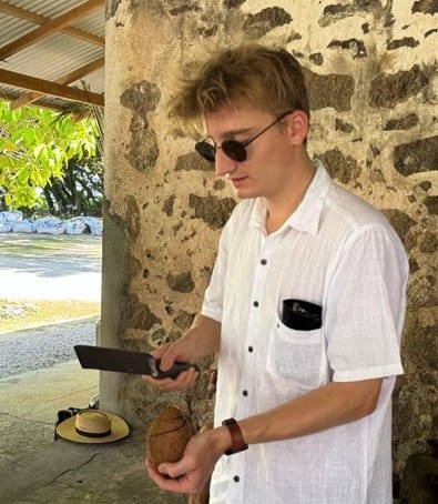 Studiosus-Reiseleiter Tim B. Boroewitsch in Aktion, als er auf einer Reise eine Kokosnuss für seine Gäste öffnet.