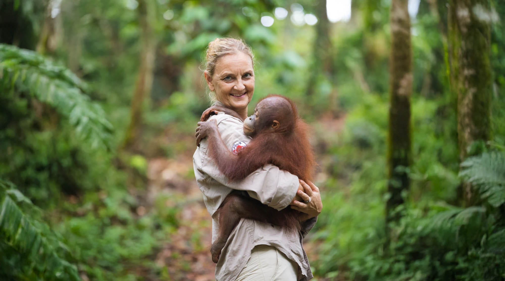 Eine Teirärztin hält einen Orang-Utan auf dem Arm.