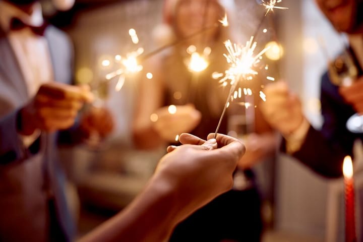 Vier Personen feiern Silvester mit Wunderkerzen in der Hand.